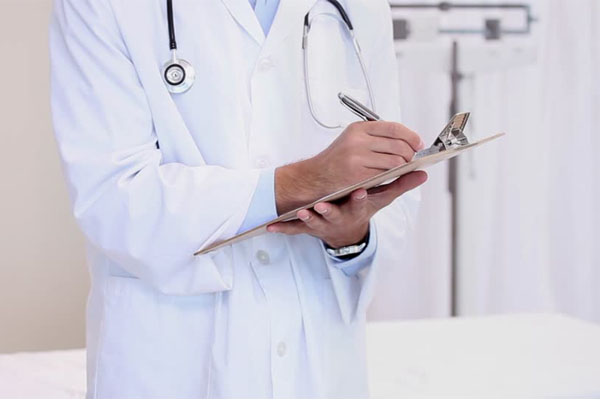 Médico con bata blanca y una tabla portapapeles en las manos haciendo una valoración preoperatoria
